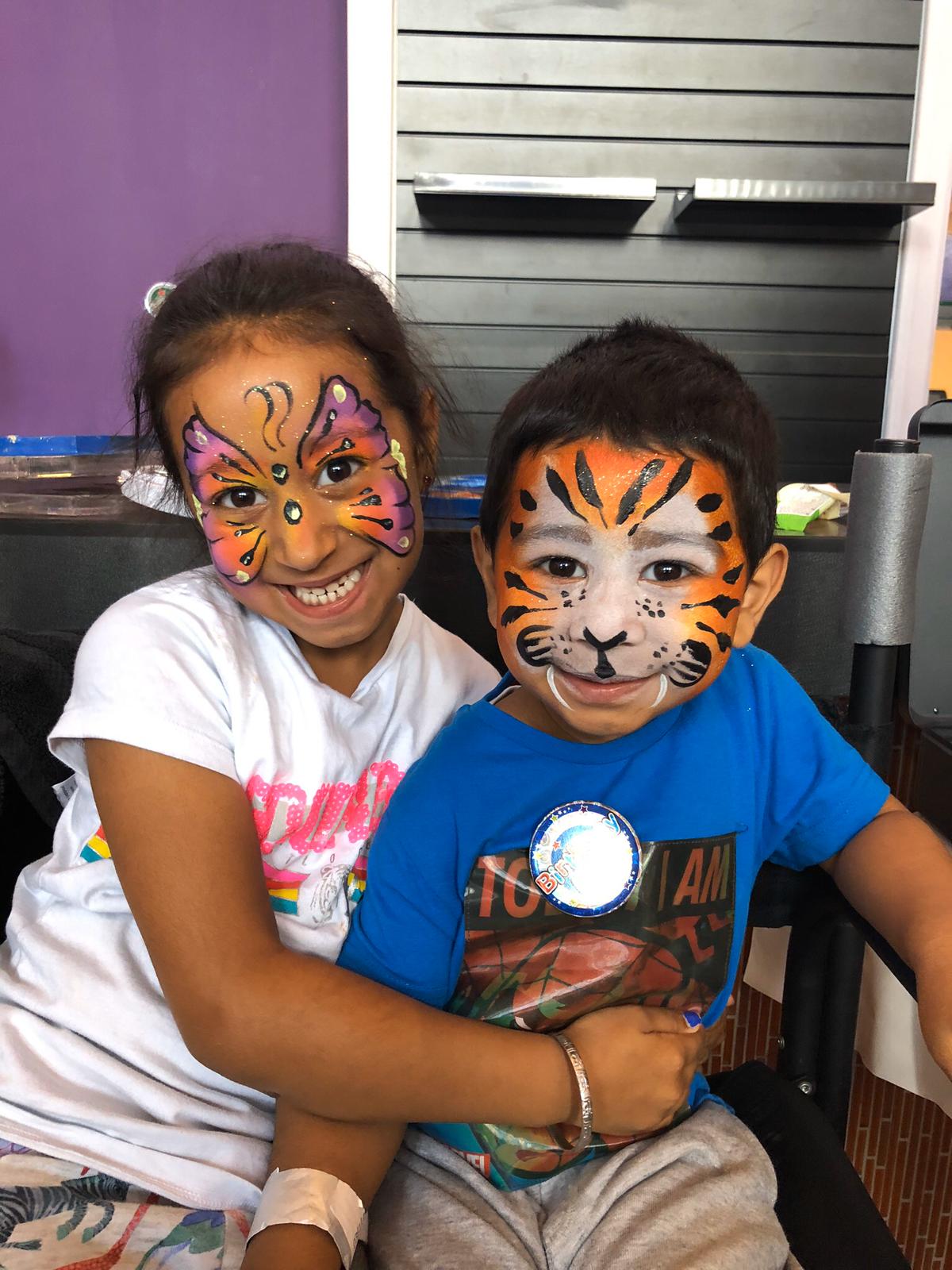 girl with butterfly face paint and boy with tiger face paint